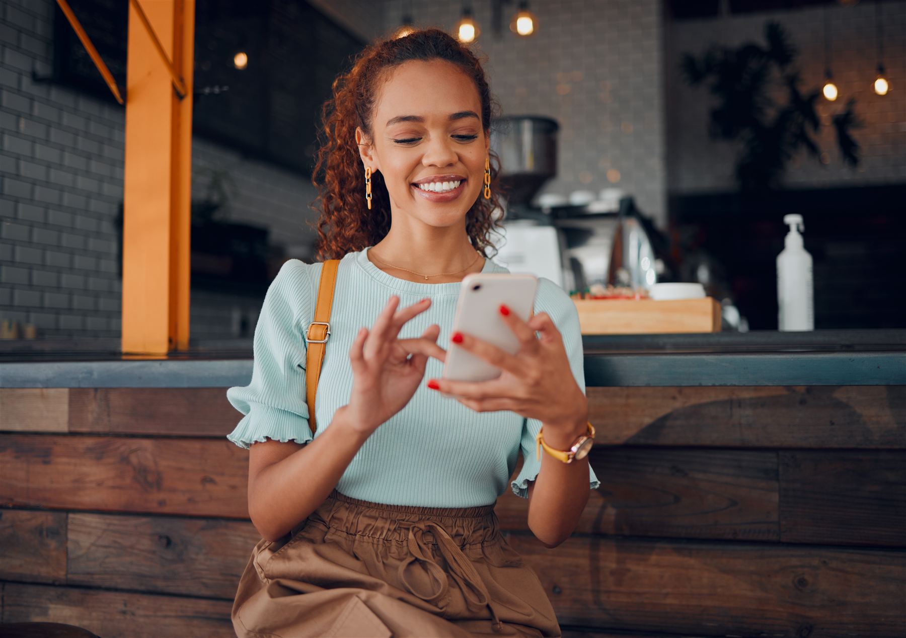 A customer smiling as she reads on her phone in a café
